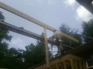 Carpenter setting a ridge beam over a new addition frame — Ice Dam Removal by Roofing Brothers in Spurger