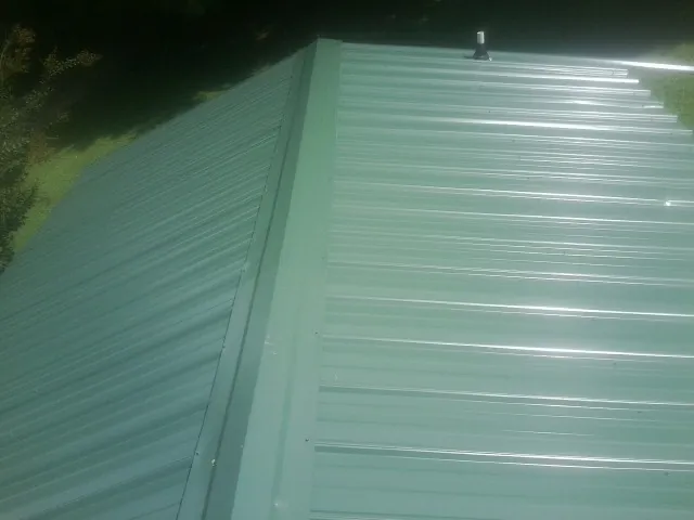 New green metal panels meeting at the ridge of a roof — Flat Roof Repair work by our crew in Spurger