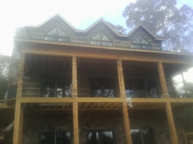 Dormers and porch framing on a large log home under construction — Roof Coating work by our crew in Spurger