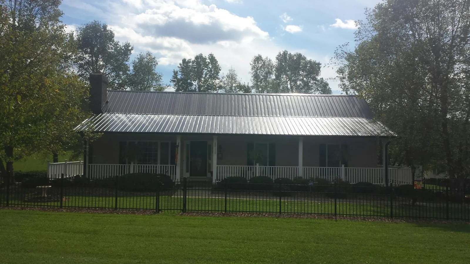 Gray metal roof on a brick ranch with a full width front porch — Gutter Guard Installation work by our crew in Spurger